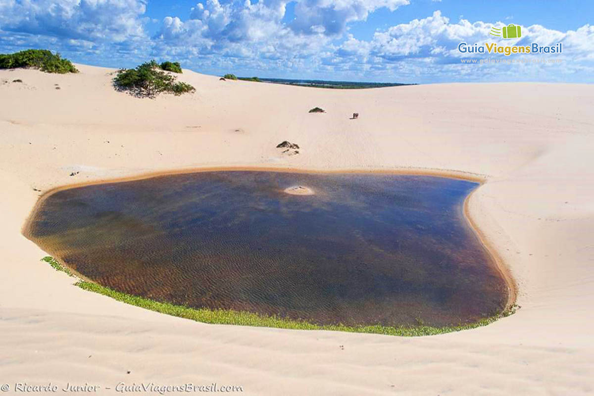 Imagem de um lago no meio das dunas.
